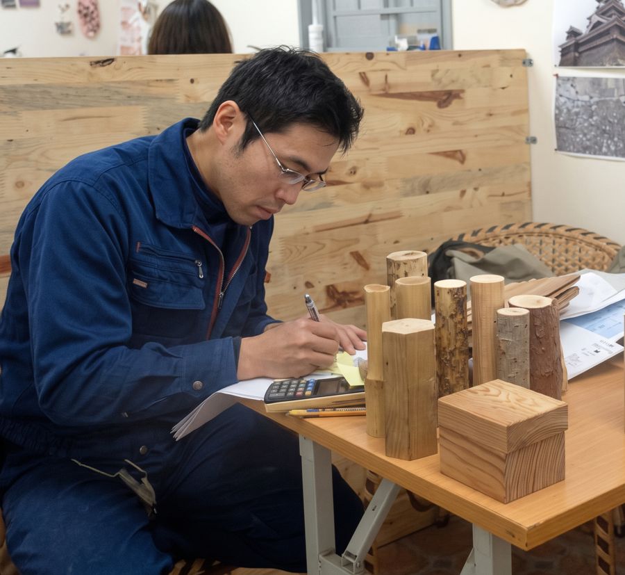 Người thợ ghi chép bên bàn có các mẫu gỗ
